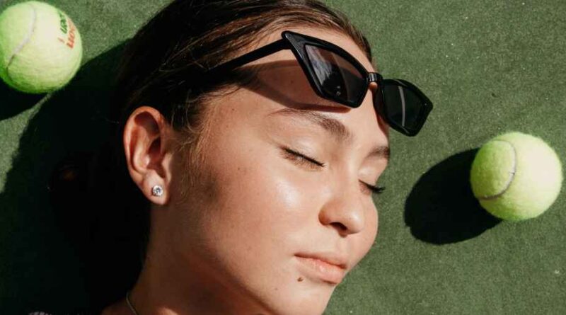 Een vrouw met haar ogen dicht, ligt tussen de tennisballen. Dit verbeeldt het concept van The Inner Game of Tennis.