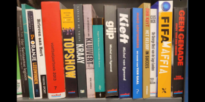 Foto van boekenkast met voetbalboeken. Waaaronder de biografieën van Willem Kieft, René van der Gijp en Patrick Kluivert.